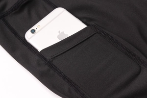 Détail de la poche latérale d'un legging de yoga noir contenant un grand smartphone