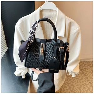 Détail d'un sac seau noir tressé avec foulard décoratif en soie et boucle dorée chic