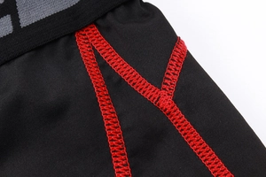 Close-up of red flatlock stitching on black elastic compression pants for men