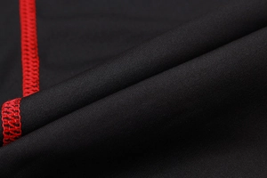 Macro view of men's compression tights showing durable red flatlock stitching on black fabric