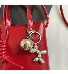 Dettaglio borsa in pelle rossa con ciondolo a forma di cane palloncino e sfera d'argento