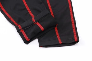Detail of red flatlock stitching on men's black compression pants for sports