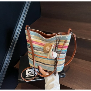 Detail of colorful striped woven tote with leather strap and baseball charm accessories