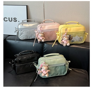 Multiple colorful Ita bags with transparent windows and plush bear charms on display