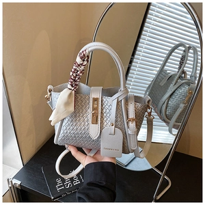 Détail du sac seau tissé argenté avec foulard décoratif en soie et fermoir rotatif doré