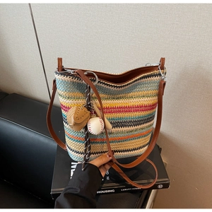 Detail of striped woven shoulder bag featuring bohemian colors and baseball charm