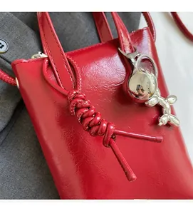 Dettaglio mini borsa rossa lucida con ciondolo a forma di cane palloncino argento e metallo