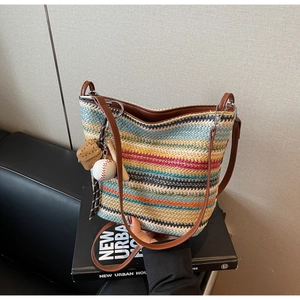 Close-up of striped woven bag with brown leather strap and baseball charm detail