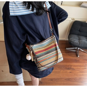 Detail of colorful striped straw shoulder bag with leather strap and baseball charm