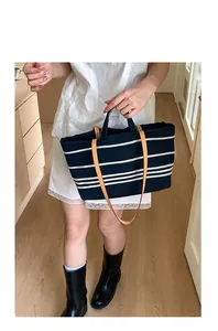 Detailed shot of striped canvas tote bag with leather straps and shoulder strap attachment