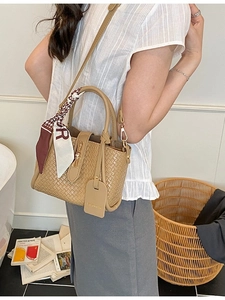 Sac seau tressé kaki avec foulard imprimé et fermoir métallique en scène d'intérieur