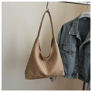 Detail of khaki woven leather shoulder bag with textured herringbone pattern and wide strap