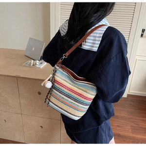 Detailed view of striped woven straw tote with leather strap and baseball charm