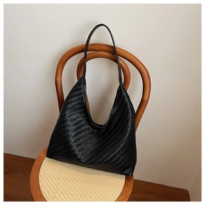 Close-up of black woven leather bucket bag featuring detailed Z-pattern craftsmanship