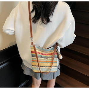 Detail of colorful striped woven shoulder bag with a cute baseball pendant