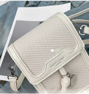 Detailed macro of cream fabric texture and heart pendant on a crossbody bag