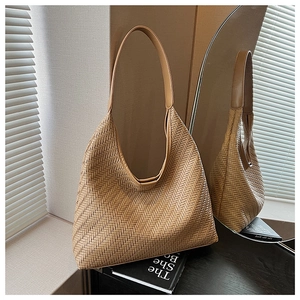 Detailed close-up of brown woven tote bag with herringbone texture and leather handle