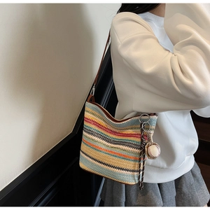 Detail of colorful striped woven tote with brown leather strap and baseball charm