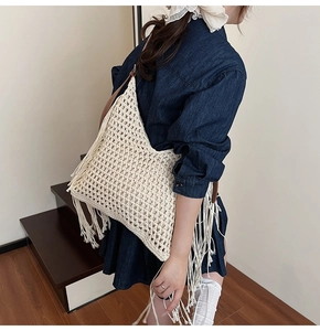 Detail of bohemian beige crochet tote bag featuring long fringes and brown leather strap