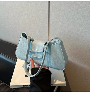 Close-up of light blue textured leather underarm bag featuring a small bow detail
