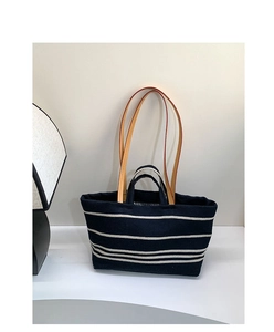 Detail of striped canvas tote with black handles and yellow leather straps on desk