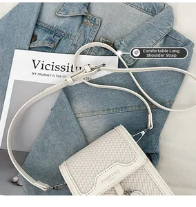 Detail of adjustable shoulder strap and metal buckle on a white woven crossbody bag