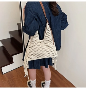 Detail of cream crochet tote bag with long tassels and brown leather strap on model