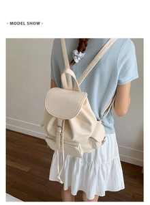 Model wearing a vintage cream leather backpack with drawstring closure and buckle detail
