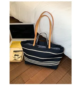 Detail of canvas tote bag showing black and white stripes with durable faux leather straps