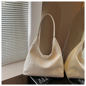 Detail of cream woven leather hobo bag with V-pattern texture near a window reflection