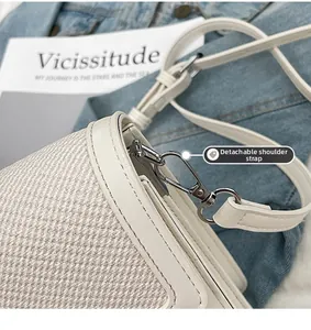 Detail of detachable shoulder strap with silver metal hook on beige fabric bag