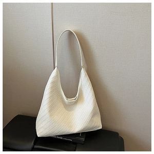 Close-up of cream white leather hobo bag with detailed woven texture on black stool