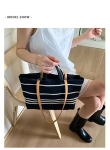 Detail of navy blue striped canvas tote bag with brown leather handles and shoulder strap