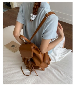 Brown vintage leather backpack with drawstring and flap on model in lifestyle setting