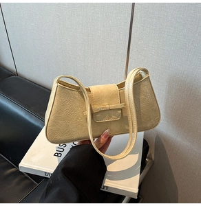 Close-up of beige wrinkled leather baguette bag with knot detail and dual straps