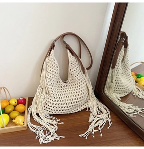 Close-up of bohemian woven tote bag featuring long fringes and brown leather strap