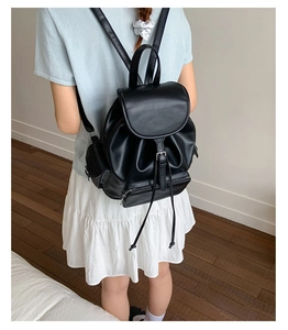 Detail of black matte PU leather backpack with flap drawstring closure and zip pocket