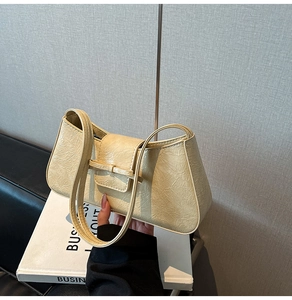 Detail of cream pleated leather underarm bag with an elegant bow accent and dual straps