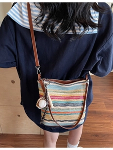 Striped woven shoulder bag with baseball charm and brown strap for vacation fashion
