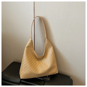 Close-up of khaki woven tote bag showing detailed herringbone pattern and shoulder strap