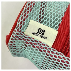 Macro shot of red mesh fabric texture and woven music pouch label on a stylish mini bag