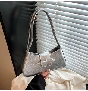 Macro detail of silver metallic shoulder bag with crinkled texture and decorative bow