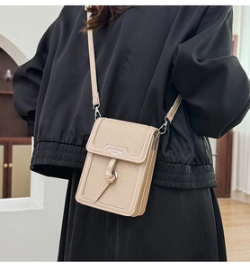 Detail of woven fabric cross-body bag with leather trim and decorative metal ring