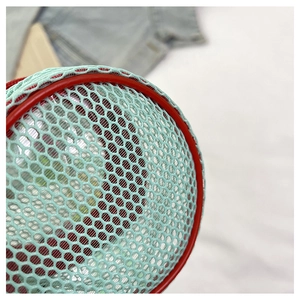 Detail of teal honeycomb mesh fabric with contrasting red cylindrical piping and stitching