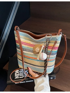 Colorful striped woven tote bag with brown leather straps and baseball charm detail