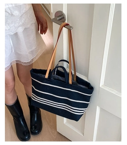 Detail view of large canvas tote bag with navy blue stripes and leather shoulder straps