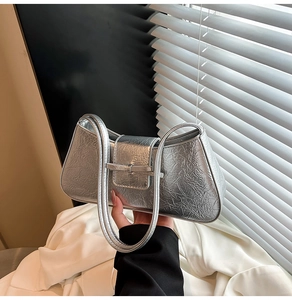 Detail shot of silver metallic shoulder bag featuring pleated texture and buckle