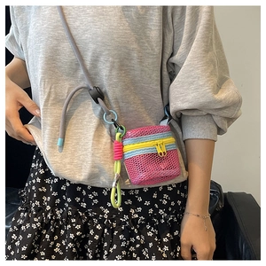 Detail of mini mesh crossbody bag in rose red with yellow zipper and colorful cord strap