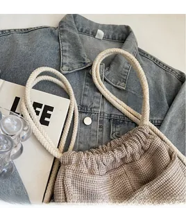 Detail of woven bucket bag with thick rope shoulder strap on lifestyle background