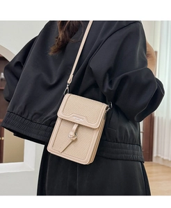 Close-up of mini woven beige crossbody phone bag with leather strap and metal buckle detail